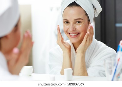 Happy Woman With Toothy Smile Pampering Eye-cream