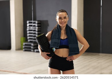 Mujer feliz con la toalla y el rodillo de la espuma en estudio de la aptitud