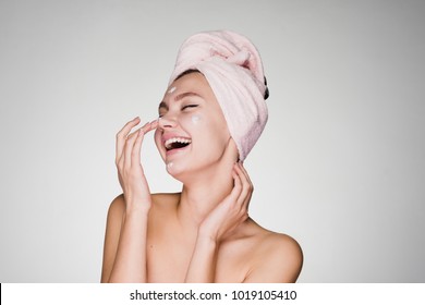 Happy Woman With A Towel On Her Head Applying Cream On Face