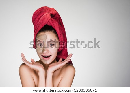 happy woman with a towel on her head applied a mask to her face
