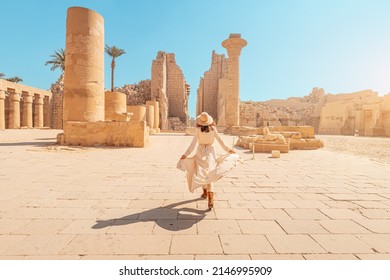 Happy woman traveler explores the ruins of the ancient Karnak temple in the heritage city of Luxor in Egypt. Giant row of columns with carved hieroglyph