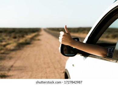 Happy Woman Traveler Showing Thumbs Up Out Of Car Window, Enjoys Road Trip In A Car During Summer Holidays In Australia. Concept Of Freedom, Fun And Adventure