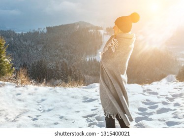 Happy woman traveler in snowy sunny day stay on top of mountain and looking on beautiful winter view.