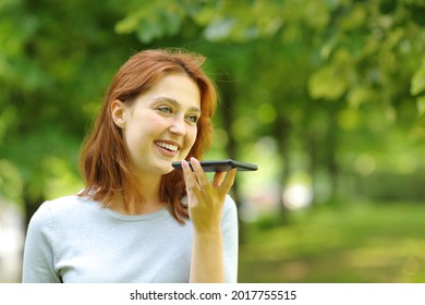 Happy Woman Uses Voice Recognition On Smart Phone Walking In A Park