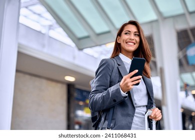 Happy woman using app on mobile phone at train station. Copy space.