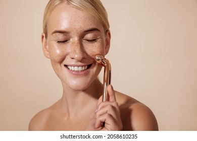 Happy Woman Using Facial Roller. Young Female Doing Skincare Routine.