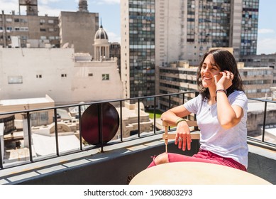 Happy woman using her mobile phone in the balcony during sunny day.