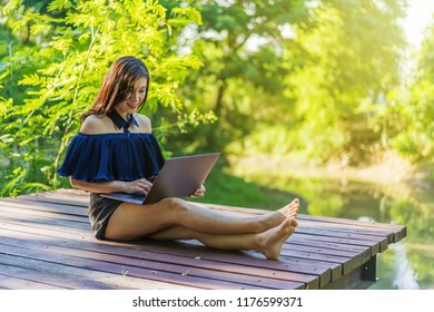 Happy Woman Using Laptop Computer On A Wooden Jetty