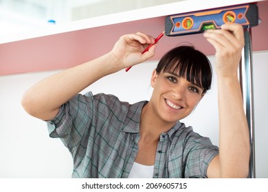 Happy Woman Using Leveling Tool On Furniture