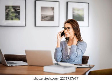 Happy woman using mobile phone and laptops for work. Confident business woman working from home. Home office.  - Powered by Shutterstock