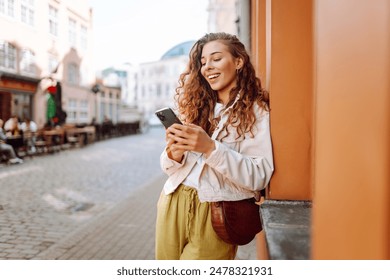 Happy woman using phone walking in city street. Lifestyle, travel, tourism, technology, blogging, communication concept.