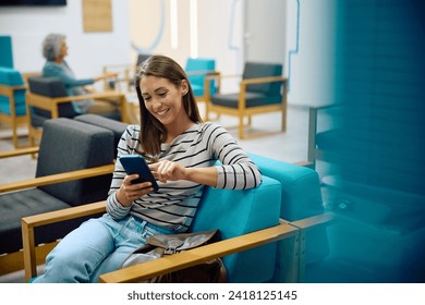 Happy woman using smart phone while waiting for doctor's appointment at medical clinic. Copy space. - Powered by Shutterstock