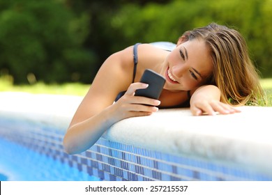 Happy woman using a smart phone in a poolside of her garden pool in summer - Powered by Shutterstock