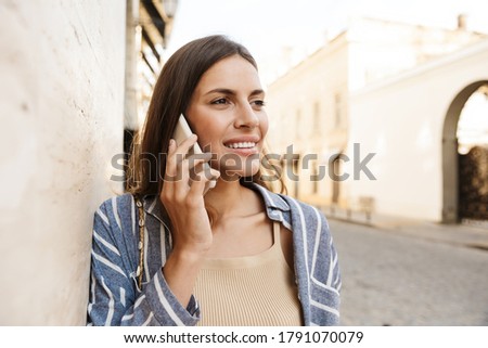 Happy woman using a smart phone on the street