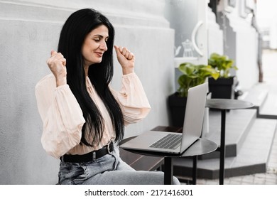 Happy Woman With Vitiligo Hands And Laptop In Cafee Outdoor. Girl Rejoices About Winning Prize Online. Hands With Vitiligo Skin Pigmentation. Lifestyle With Skin Seasonal Disease