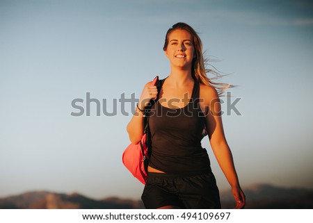 Happy woman walking with a sports bag on the shoulder. Sports concept.