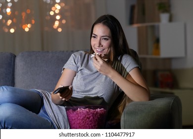 Happy Woman Watching Tv In The Night Sitting On A Couch In The Living Room At Home