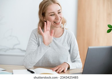 Happy woman waving hand at video call look at laptop display. Student start distant meeting with teacher on computer, studying at online courses take private lesson. Internet connection, communication - Powered by Shutterstock