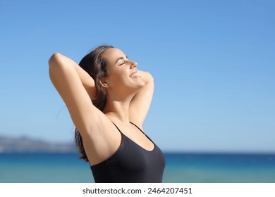 Happy woman with waxed armpit breathing fresh air on the beach a sunny day - Powered by Shutterstock