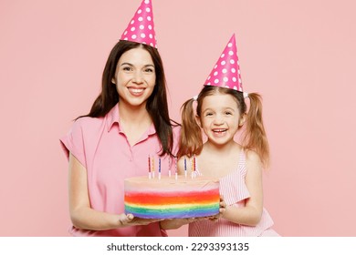 Happy woman wearing casual clothes with child kid girl 6-7 years old. Mother daughter hold cake blow out candles, celebrate birthday isolated on plain pastel pink background. Family parent day concept - Powered by Shutterstock