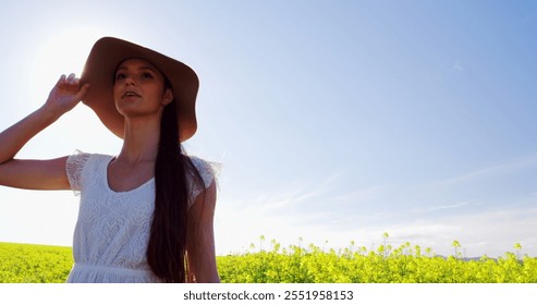 Happy woman wearing hat and walking in mustard field on a sunny day - Powered by Shutterstock