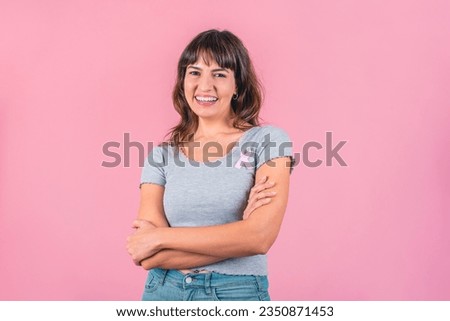 Happy woman wearing a pink breast cancer awareness ribbon while looking at camera