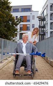 Happy Woman In Wheelchair With Nurse On A Ramp