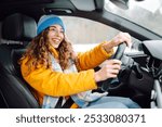 Happy woman in winter outfit driving car. The concept of transport, lifestyle.