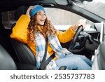 Happy woman in winter outfit driving car. The concept of transport, lifestyle.