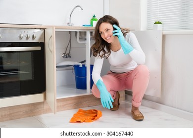 Happy Woman Wiping Leaking Water While Talking On Mobile Phone