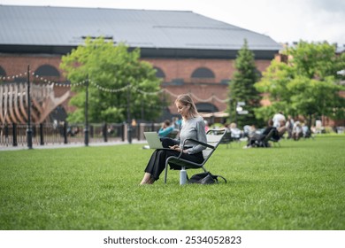 Happy woman in wireless earbuds working on laptop with thermos in summer park. Video chat, web conference, multitasking with entertainment, balancing work and nature, tech savvy, leisurely workflow - Powered by Shutterstock