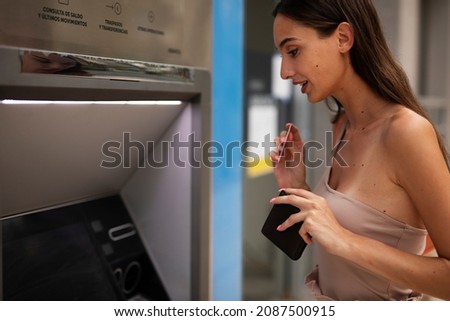 Happy woman withdrawing money from credit card. Young woman using ATM machine	