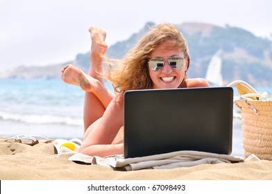 Happy Woman Is Working On Laptop On Beach