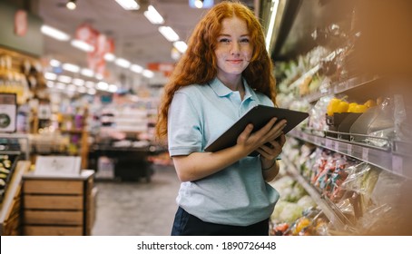 Happy Woman Working In A Supermarket. Caucasian Female Grocery Store Employee With A Digital Tablet.