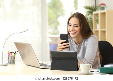 Happy woman working using multiple devices on a desk at home