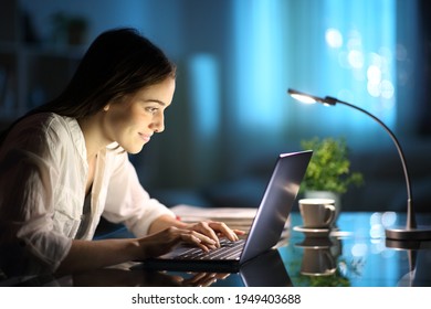 Happy Woman Writing On Laptop Keyboard On A Desk In The Night At Home