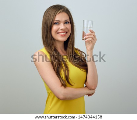 Happy woman in yellow dress holding water glass. isolated female portrait.