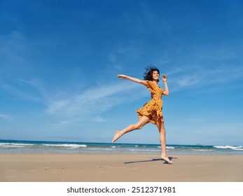 Happy woman in yellow dress jumping with outstretched arms on sandy beach on a sunny day - Powered by Shutterstock