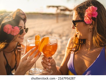 Happy women best friends drink orange fruit cocktails on the beach at sunset - drink, alcohol, vacation lifestyle concept - Powered by Shutterstock