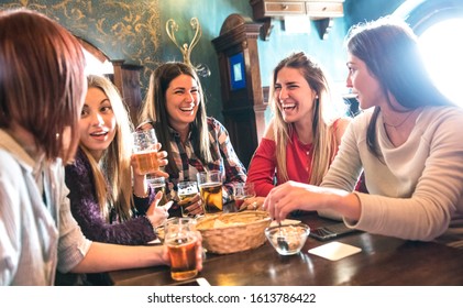 Happy women drinking beer at brewery restaurant - Female friendship concept with young girlfriends enjoying time together and having genuine fun at cool vintage pub - High iso image with soft focus