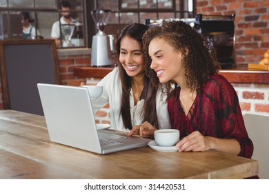 Happy Women Friends Drinking Coffee And Looking At Laptop Outside At A Cafe