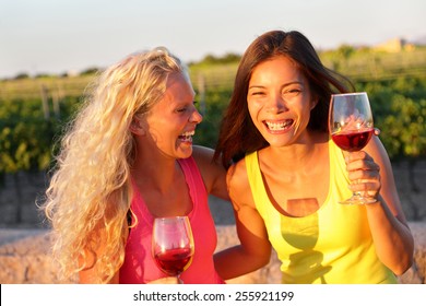 Happy Women Friends Drinking Red Wine Laughing In Vineyard In Summer. Young Laughing Girlfriends Drinking Rose Wine From Glass Outside.