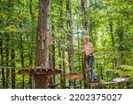 Happy women girl female gliding climbing in extreme road trolley zipline in forest on carabiner safety link on tree to tree top rope adventure park. Family weekend children kids activities concept