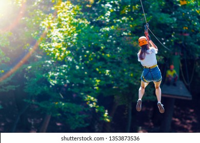 Happy women girl female gliding climbing in extreme road trolley zipline in forest on carabiner safety link on tree to tree top rope adventure park. Family weekend children kids activities concept - Powered by Shutterstock