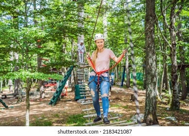 Happy Women Girl Female Gliding Climbing In Extreme Road Trolley Zipline In Forest On Carabiner Safety Link On Tree To Tree Top Rope Adventure Park. Family Weekend Children Kids Activities Concept