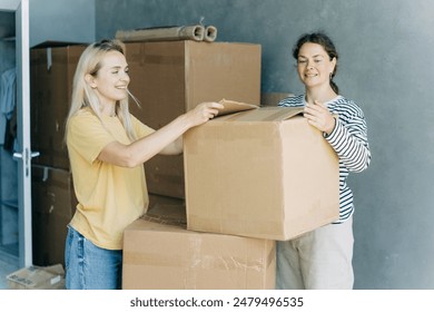 Happy women having fun while unpacking boxes and stuff while moving in a new home. - Powered by Shutterstock