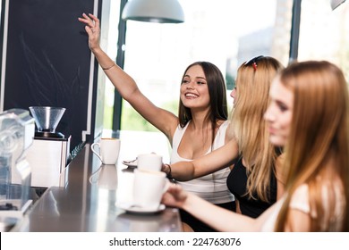 Happy women holding coffee cup while calling waiter