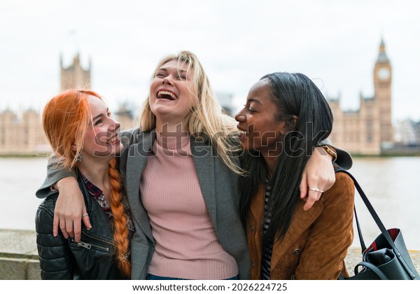Happy women laughing and having fun together in\
London - Three young women, multiracial group, hugging and laughing\
together - Best friends sharing happiness, lifestyle and friendship\
concepts