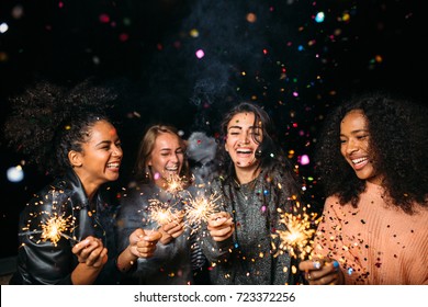 Happy women at night. Laughing friends with sparklers under confetti. - Powered by Shutterstock