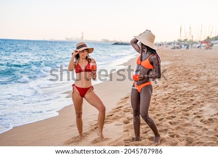 Happy women in swimwear and sunhats on beach